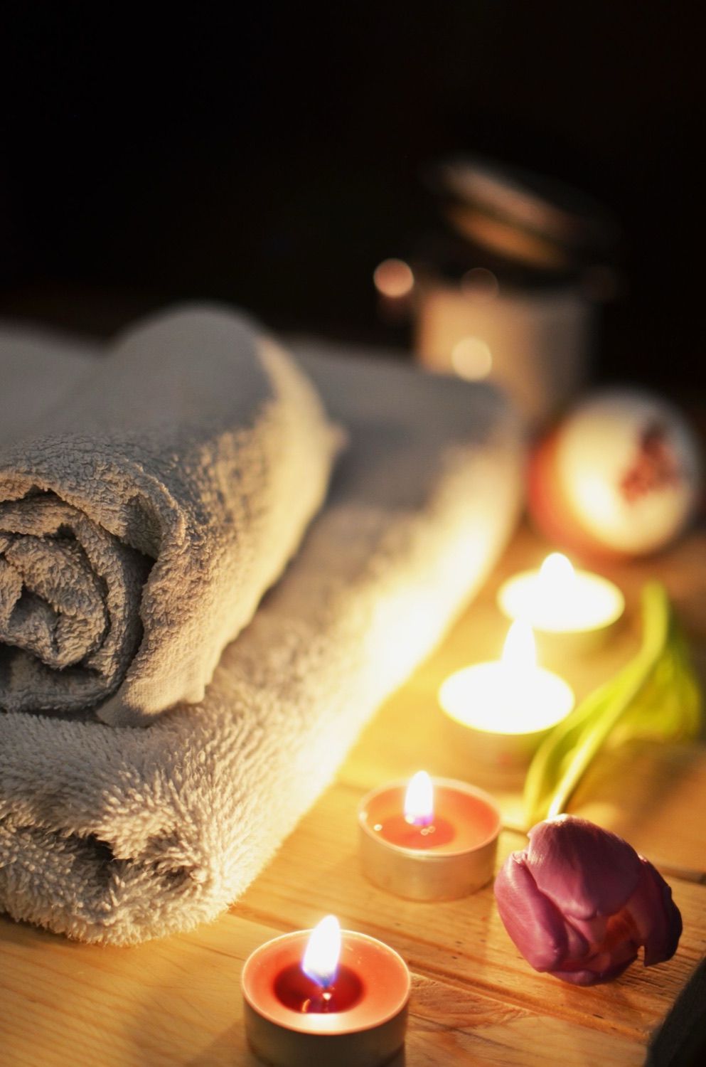 Rolled towels and lit candles in warm, low light.