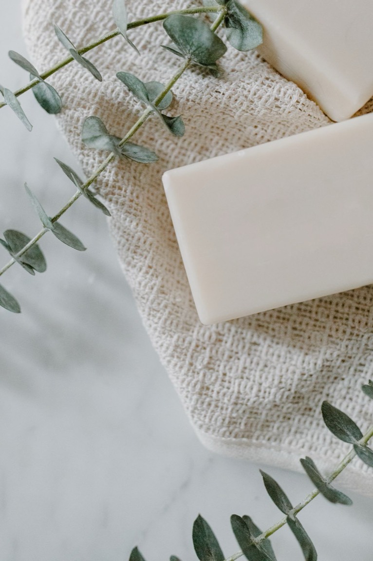 Soap bars and eucalyptus sprigs on a pale marble surface.