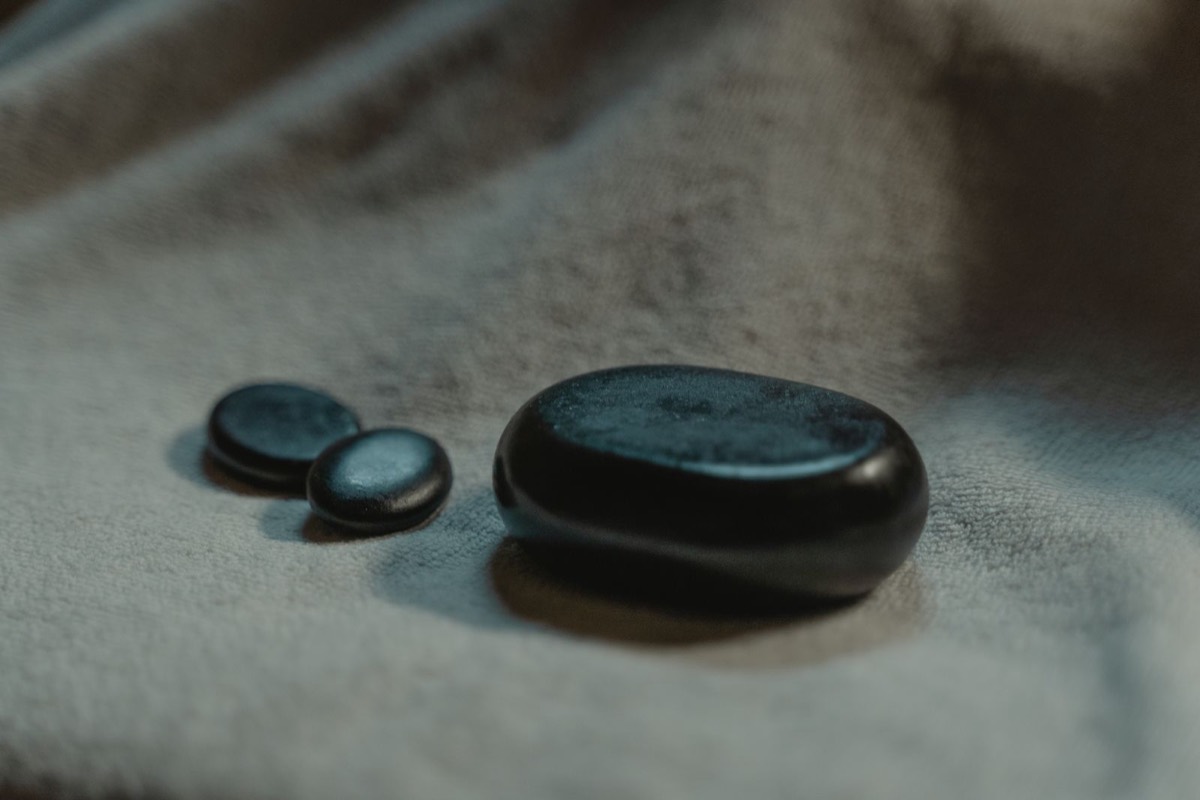 Smooth black massage stones resting on soft grey fabric.