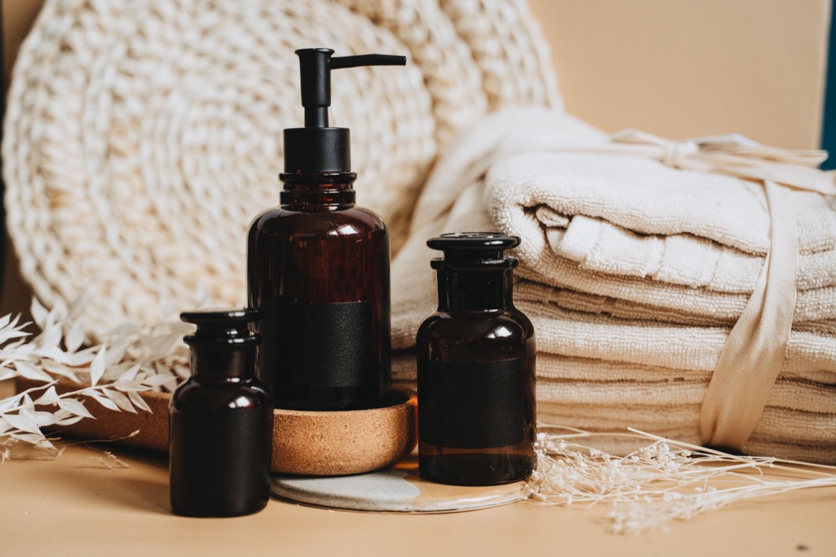 Amber apothecary bottles beside neatly folded towels and dried flowers.